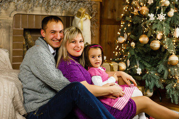 Happy family with Christmas present near the Christmas tree