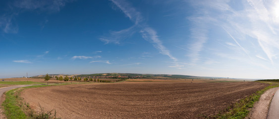 Fototapeta na wymiar Road and field on land, near small village in background