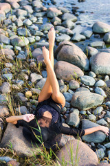 beautiful model in bikini lying on rocky beach