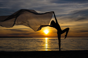 Fototapeta na wymiar silhouette of slim sexy girl posing with scarf on the beach