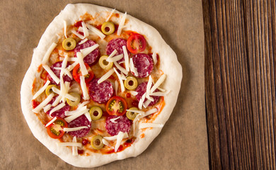 Pizza on a wooden background, before baking.