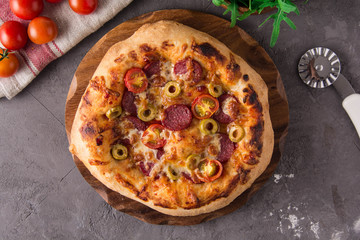 Pizza with salami, olives, tomatoes.