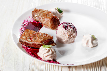Duck breast with cherry pomegranate sauce on white plate. wooden background.