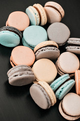 Colorful french macaroons or macarons on black wooden table. Space for text.