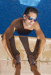 Hombre atractivo dentro de la piscina sujetando zapatos de mujer