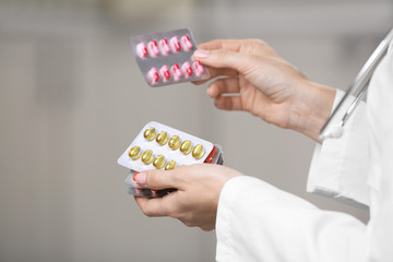 Woman holding blisters with pills on blurred background, closeup