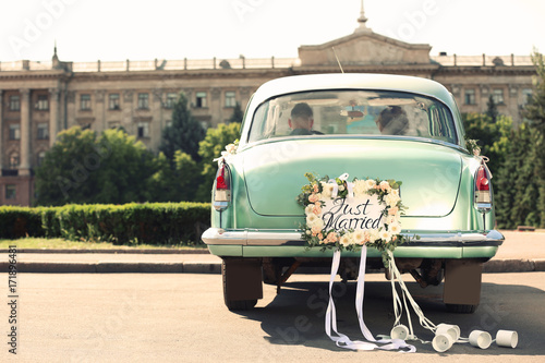 "Wedding couple in car decorated with plate JUST MARRIED and cans