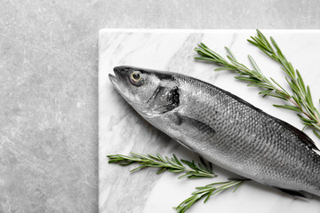 Fresh fish with rosemary on gray background