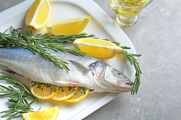 Fresh fish stuffed with rosemary and slices of lemon on table