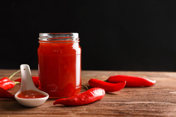 Composition with chili sauce on wooden table