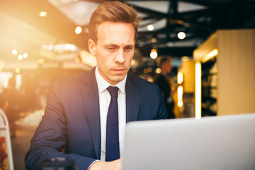 Focused young businessman sitting in a cafe working online