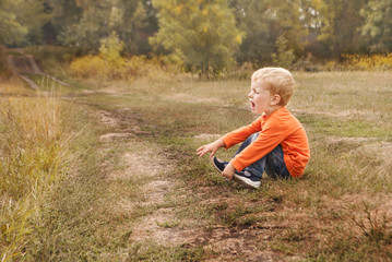 Little boy the kid in blue jeans crying bitterly, sitting on the ground