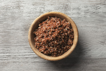 Bowl with boiled quinoa grains on wooden table