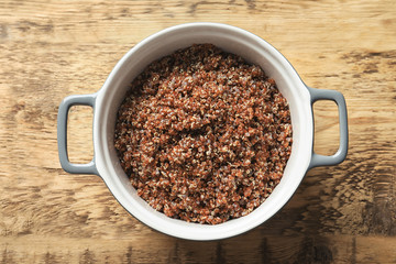 Pot with boiled quinoa grains on wooden table
