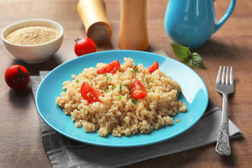 Plate with boiled quinoa grains on wooden table