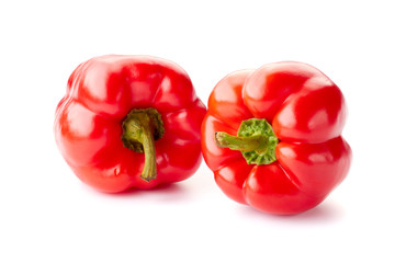 Two ripe red bell peppers over white