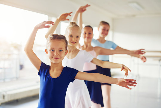 Young ballerinas dancing and looking at camera in class