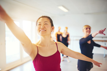 Smiling young woman leading seniors in a ballet class