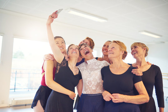Group of laughing women taking selfies in a dance studio