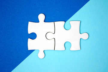 Two puzzle pieces connect on blue geometry color paper. Minimal style. Flat lay. Symbol of association and connection. business strategy.