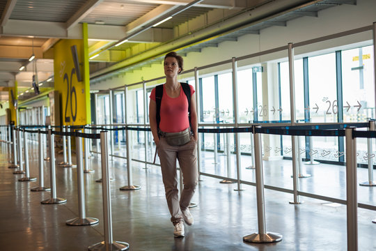Young woman with luggage waiting in the airport hall her plane