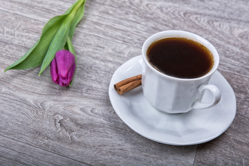 A cup of tea with cinnamon and purple tulips