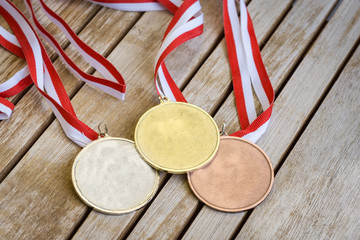Gold, silver and bronze medals at wooden texture table with white and red ribbon - 171903615