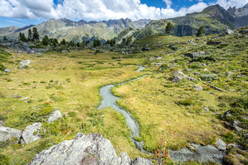 un ruisseau de montagne avec un rocher en premier plan et des montagnes en arrière plan