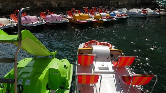 Catamarans sway on the waves at the pier on Lake Garda on a summer day
