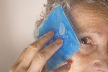 Senior woman with ice on head for headache