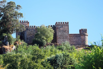 Fototapeta na wymiar Castle wall with battlement and fortified tower in clear and sunny autumn day in a village named 