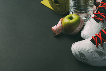Sport and diet concept with sneakers, measuring tape and water 