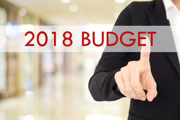 Businesswoman hand touch 2018 budget  button over blur office background with copy space, new year business concept