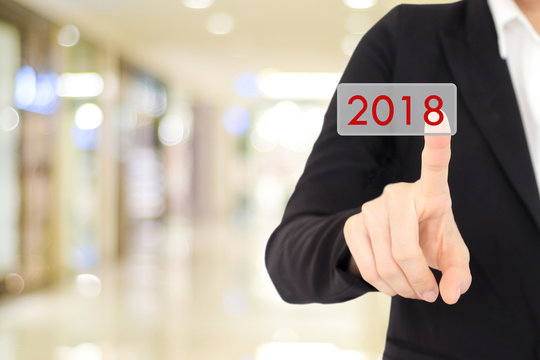 Businesswoman hand touch 2018 button over blur office background, new year business concept