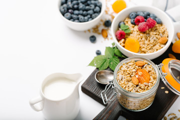 Homemade granola and healthy breakfast ingredients - milk, dried fruit and berries