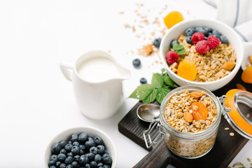 Homemade granola and healthy breakfast ingredients - milk, dried fruit and berries