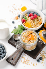 Homemade granola and healthy breakfast ingredients - milk, dried fruit and berries