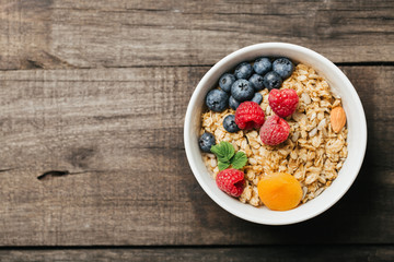 Homemade granola with dried fruit and berries on wooden background