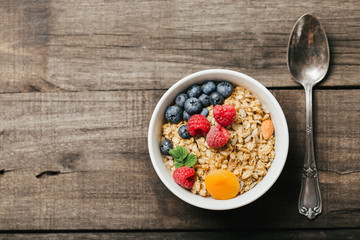 Homemade granola with dried fruit and berries on wooden background