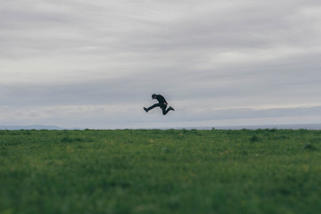 man jumping with moody clouds