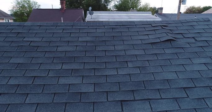 A simulated video feed of a roof inspector's drone examining a house's damaged shingled roof after a storm.  	