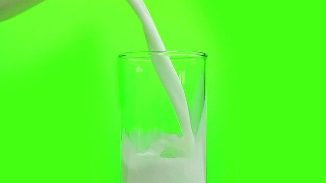 fresh white milk pouring into drinking glass on chroma key green screen background, shooting with slow motion, diet and healthy nutrition concept