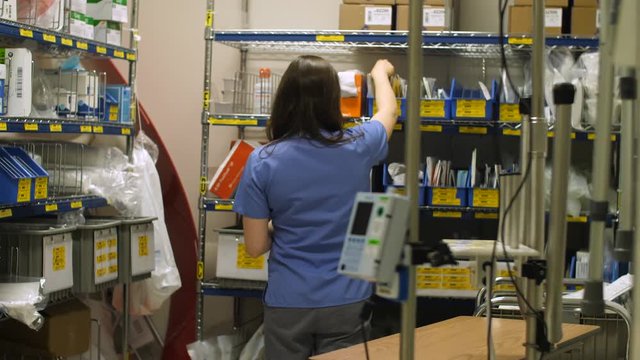 A nurse collects medical supplies from a storage room in a hospital.