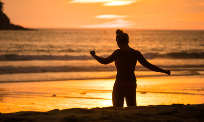 Fototapeta premium Silhouette Women are doing activities on the beach with sunset.