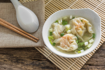 shrimp wonton with soup in a ceramic bowl on old and crack wooden surface. delicious chinese food.