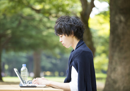 公園でパソコンを操作する男性　ビジネス＆ライフスタイル汎用