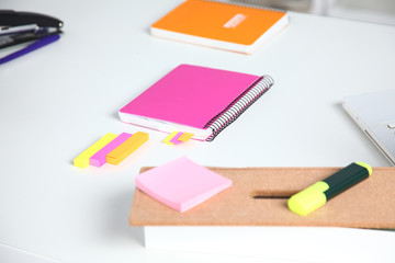 Closeup of white desktop with notepads, pen, coffee cup and other items. Selective focus.