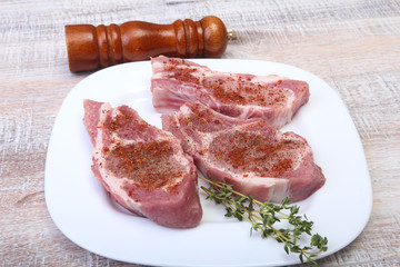 Raw pork chops and spice grinder on cutting board. Ready for cooking.