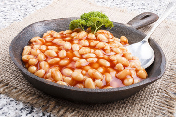 warm baked beans in tomato sauce served in a cast iron pan