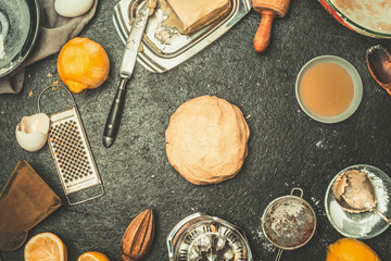 Baking background with dough  , kitchen tolls and ingredients: Flour,eggs,butter on dark rustic background, top view